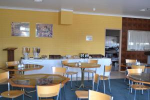 a restaurant with tables and chairs and a yellow wall at Chadstone Executive Motel in Oakleigh