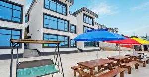 2 Picknicktische mit Sonnenschirmen vor einem Gebäude in der Unterkunft Ongjin Guardians Pool Villa in Sojang-gol + 7 Fotos