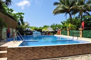 a large swimming pool with a brick wall and trees at Aloha Ocean View Resort in Pandan