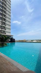 une grande piscine bleue à côté d'un grand bâtiment dans l'établissement Mutiara Bali Residence Melaka, à Malacca