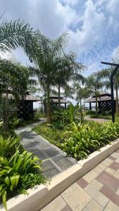 une passerelle dans un jardin planté de palmiers et de plantes dans l'établissement Mutiara Bali Residence Melaka, à Malacca