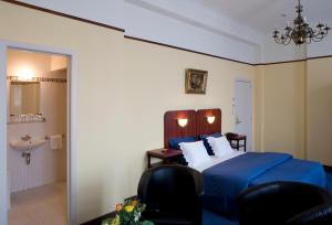 a bedroom with a bed and two chairs and a sink at Hotel Antwerp Billard Palace in Antwerp
