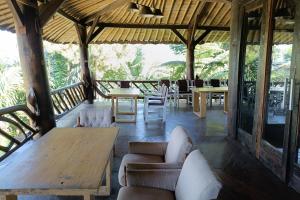 un soggiorno con tavoli e sedie e un tavolo di legno di Mendulang by Belza a Bandung