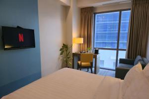 a hotel room with a bed and a desk and a television at Resort-style Comfort Near Mactan Airport in Punta Engaño