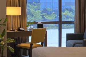 a hotel room with a desk and a bed and a window at Resort-style Comfort Near Mactan Airport in Punta Engaño