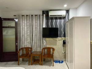 a room with two chairs and a table and a tv at Duc Long Airport Hotel in Ho Chi Minh City