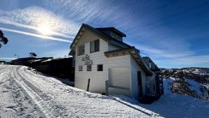 a building in the snow with the sun in the sky at Alpine Haven 5 in Mount Hotham