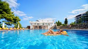 une femme qui se pose sur un radeau dans une piscine dans l'établissement Alexander the Great Beach Hotel, à Kriopigi