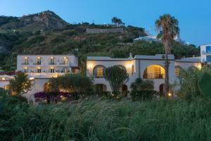 a large white house with a hill in the background at Hotel CASA LA VIGNA in Ischia