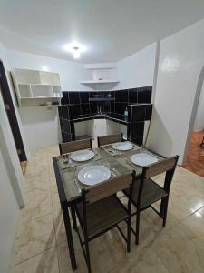 a dining room table with three chairs and a kitchen at Alexa's Apartments in El Nido