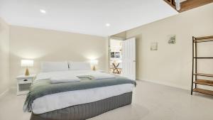 a white bedroom with a large bed in it at The Loft in Culburra Beach