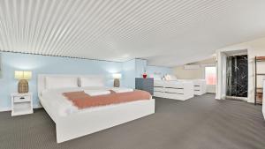 a bedroom with a white bed and a blue wall at The Loft in Culburra Beach