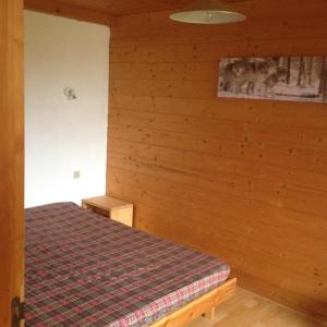 ein Schlafzimmer mit einem Bett und einer Holzwand in der Unterkunft Mirabelle C8 in Xonrupt-Longemer