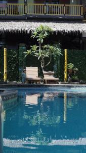 a pool with two chairs and a tree next to a building at Grand Desa Resort in Cimaja