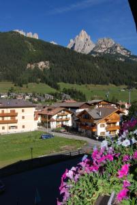 a view of a town with mountains and flowers at Park Hotel Mater Dei in Pozza di Fassa