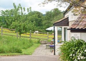 a building with a table and chairs and horses in a field at Old Orchard Cottage in Colyton