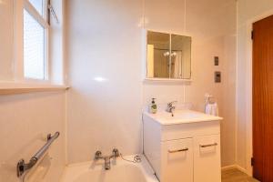 a bathroom with a tub and a sink and a bath tub at Cosy on Goldfinch in Ohakune +7 photos
