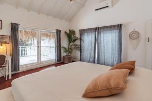 a white bedroom with a large bed and a window at European-Inspired Villa Near Beach & Dining in Gili Trawangan