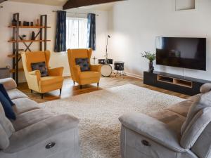 a living room with a couch and two chairs and a television at Barn Court in Rackheath