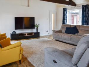 a living room with a couch and a television at Barn Court in Rackheath