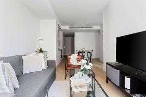 Una sala de estar con un sofá gris y una mesa. en A Cozy 2BR Apt Right on Buzzing Chapel Street, en Melbourne