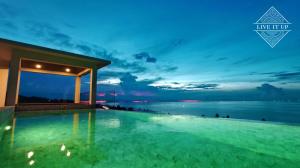 una piscina notturna con l'oceano sullo sfondo di Santi Vista Villas a Ko Samui