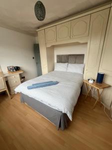 ein Schlafzimmer mit einem großen weißen Bett und Holzboden in der Unterkunft The Bungalow by SJP - Twin Room in Kettering