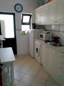 cocina con armarios blancos, fregadero y microondas en Erike Guest House, en Carvoeiro