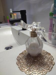 een badkamerwastafel met een glazen fles op een onderzetter bij L'appart Millau Centre-Ville - Gite in Millau