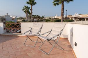 two chairs sitting on a patio with palm trees at New Vista Blu Alghero in Alghero