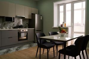 a kitchen with a table and chairs and a kitchen with a refrigerator at Apart-Hotel Kareff in Oral