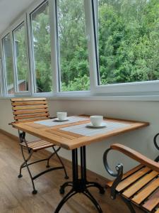 a table with two cups and two chairs in a room with windows at Apartamentų nuoma Juodkrantėje in Juodkrantė +9 photos