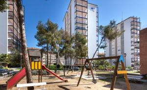 a playground in a park with tall buildings at Hola! - El Cortijo in Sitges
