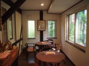 two tables and chairs in a room with windows at Guesthouse Canterbury in Naka-satsunai