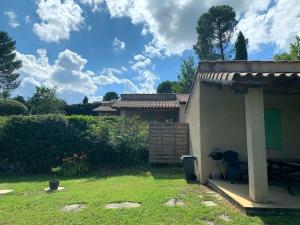 a backyard of a house with a yard with a chair at GÎTES LES LAUZIÈRES CLIMATISÉS avec PISCINE in Tauriers