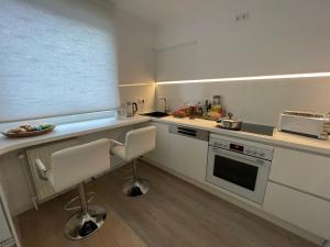 a kitchen with white cabinets and a counter with chairs at Zimmer mit zwei Einzelbetten in Borgholzhausen