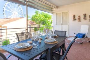 a blue table on a balcony with a ferris wheel in the background at La Vela - appartamento in centro - vista mare in Alghero