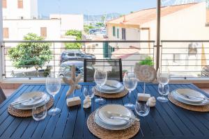 a blue table with plates and wine glasses on a balcony at La Vela - appartamento in centro - vista mare in Alghero +35 photos