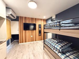 a room with two bunk beds and a flat screen tv at Nexoni Tenjin in Fukuoka