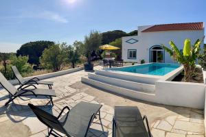 eine Terrasse mit Stühlen und einem Swimmingpool in der Unterkunft Boutique holiday home "Casa da vida doce" I Private, quiet & stylish I Pool, garden, sea view I For families, friends & couples in Lagoa
