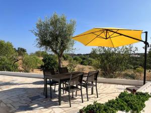 einen Tisch und Stühle mit gelbem Regenschirm in der Unterkunft Boutique holiday home "Casa da vida doce" I Private, quiet & stylish I Pool, garden, sea view I For families, friends & couples in Lagoa
