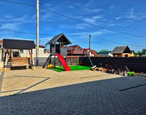 a playground with a red slide and a red slidektop at Căsuțele Denis&Lucas in Ocna Şugatag
