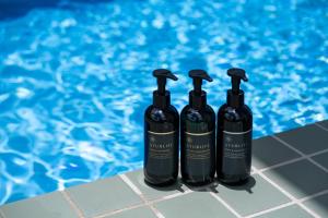 three black bottles sitting next to a swimming pool at マチナカミヤコ in Miyako Island