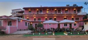 a pink building with tables and chairs in front of it at Venias Rooms in Skala Eresou