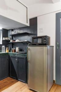 a kitchen with a stainless steel refrigerator and black cabinets at Tori 1BHK Bandra W by The Bombay Home Company in Mumbai