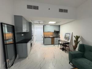 a living room with a green couch and a kitchen at Studio at Bab Al Bahr RAK in Ras al Khaimah