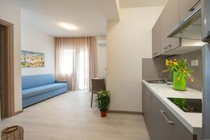 a kitchen and living room with a blue couch at Hotel Capinera in Caorle