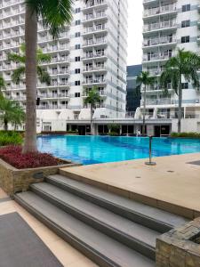 a swimming pool in a city with tall buildings at Shell Residences MOA - Josh staycation in Manila