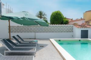 un patio avec une chaise et un parasol et une piscine dans l'établissement WELCS CASA 111 EMP con piscina, à Empuriabrava