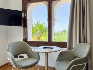Dos sillas y una mesa frente a una ventana. en Emerald Sun Hotel, en Cambrils